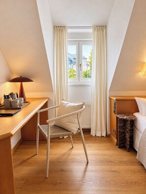 A room with a wooden desk, a chair, a bed, and a window with curtains.