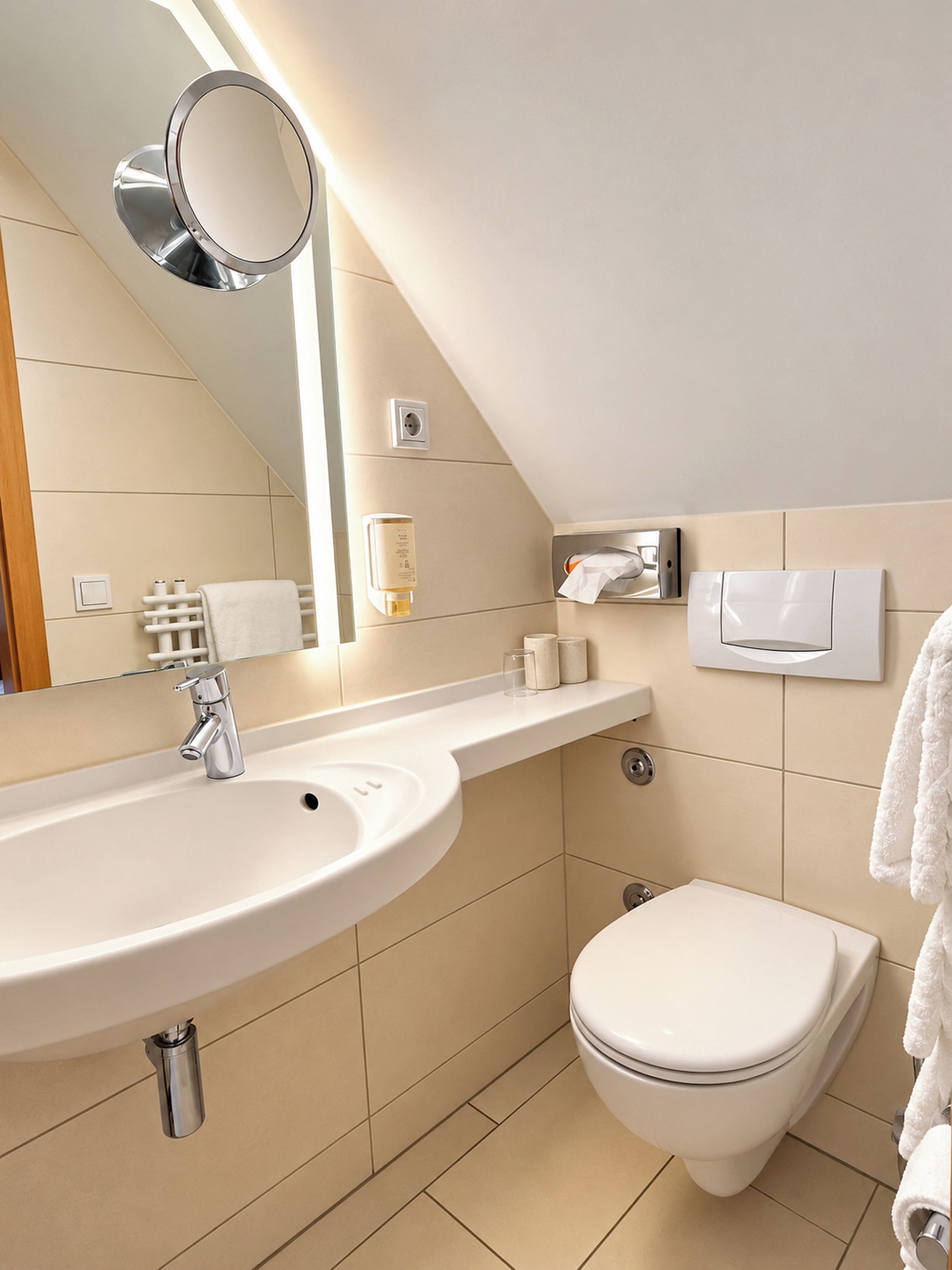 A modern bathroom with a sink, mirror, toilet, and towel rack.