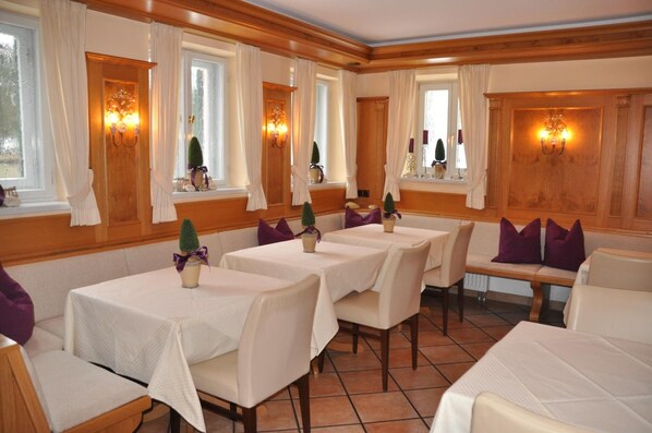 A dining area with tables and chairs, wooden paneling, and decorative lights. - Hotel Fischerhaus (Starnberg)
