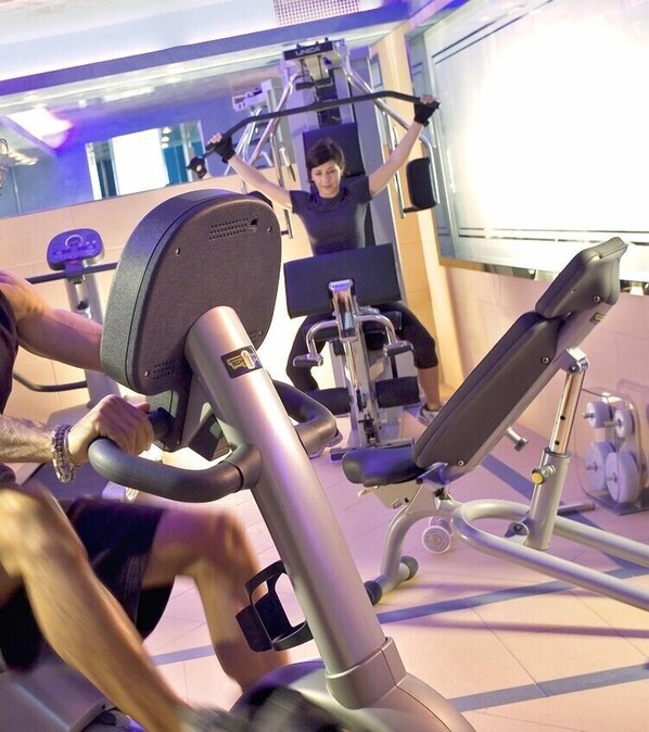Une salle de sport équipée de matériel d’exercice, notamment un vélo d’appartement et un banc de musculation.