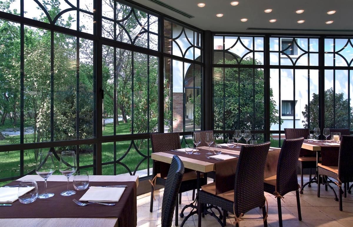 Un ristorante con tavoli e sedie, ampie finestre e vista sul verde.