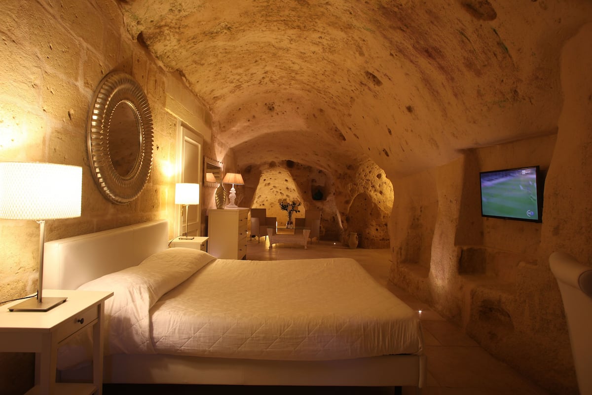 A cozy, cave-like bedroom with a large bed, a television, and a mirror on the wall.