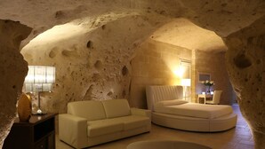 Un interior acogedor, tipo cueva, con un sofá, una cama redonda y una lámpara.
