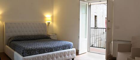 A bedroom with a bed, bedside lamp, and a door leading to a balcony.