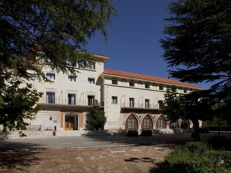 A two-story building with a symmetrical facade, large windows, and a central entrance with a wooden door.
