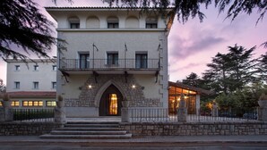Un edificio histórico con fachada de piedra, una entrada central en arco y un balcón en el piso superior.