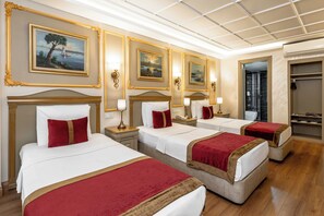 A hotel room with three beds, each with a red and gold bedspread, and a painting above each bed. - My Assos Hotel (Istanbul)