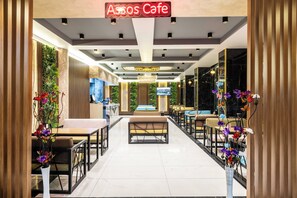 A modern cafe interior with a central seating area, a TV screen, and a neon sign. - My Assos Hotel (Istanbul)