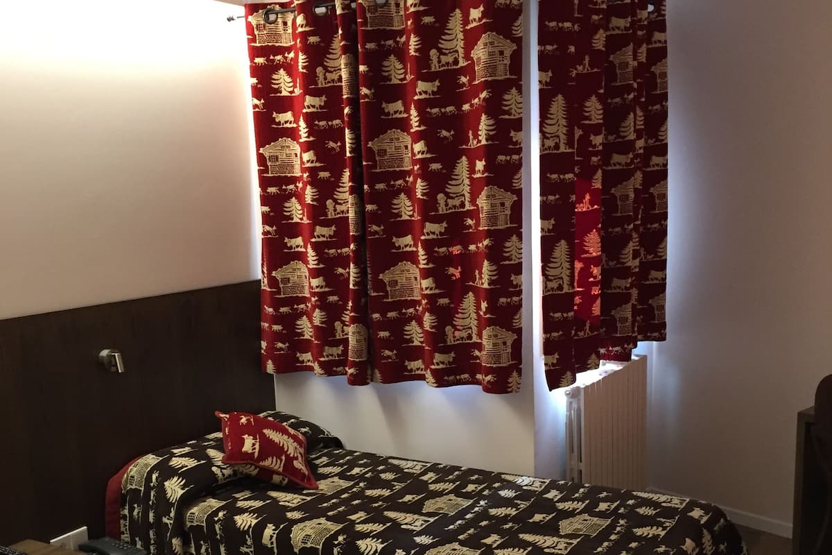 A room with a bed, a bedside table with a phone, and a lamp.
