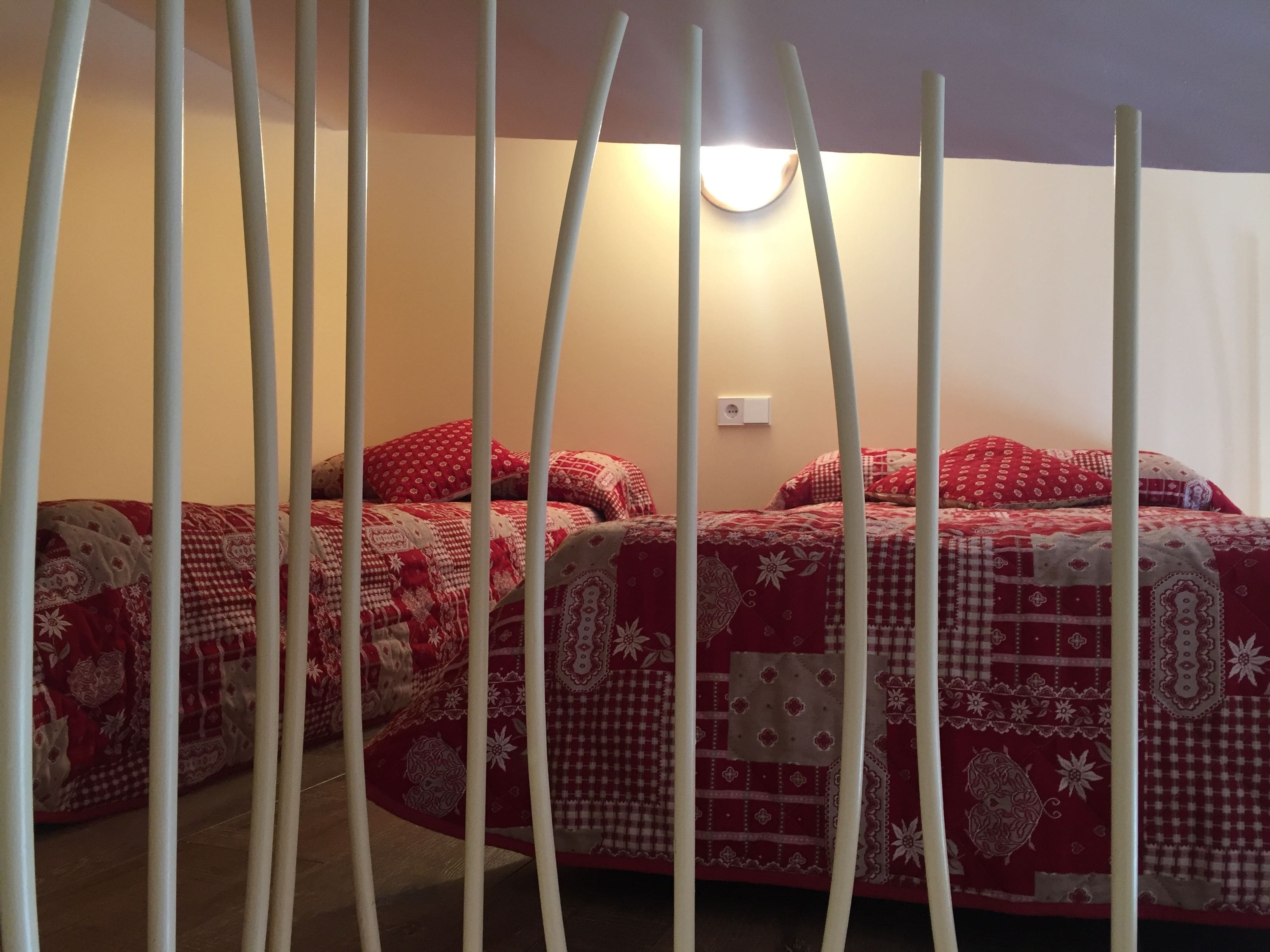Une chambre à coucher avec deux lits, chacun étant équipé de draps à motifs rouges et blancs.