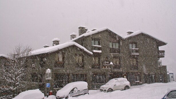 A stone building with multiple balconies and a snow-covered roof.