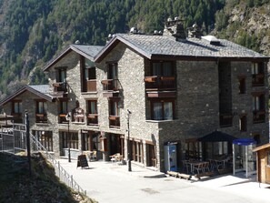 Un edificio de piedra con varios balcones, un restaurante y terraza.