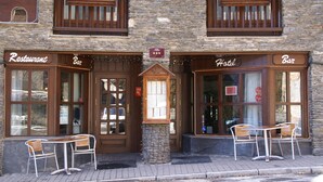 A hotel with a stone facade, wooden balconies, and a sign indicating a restaurant and bar.