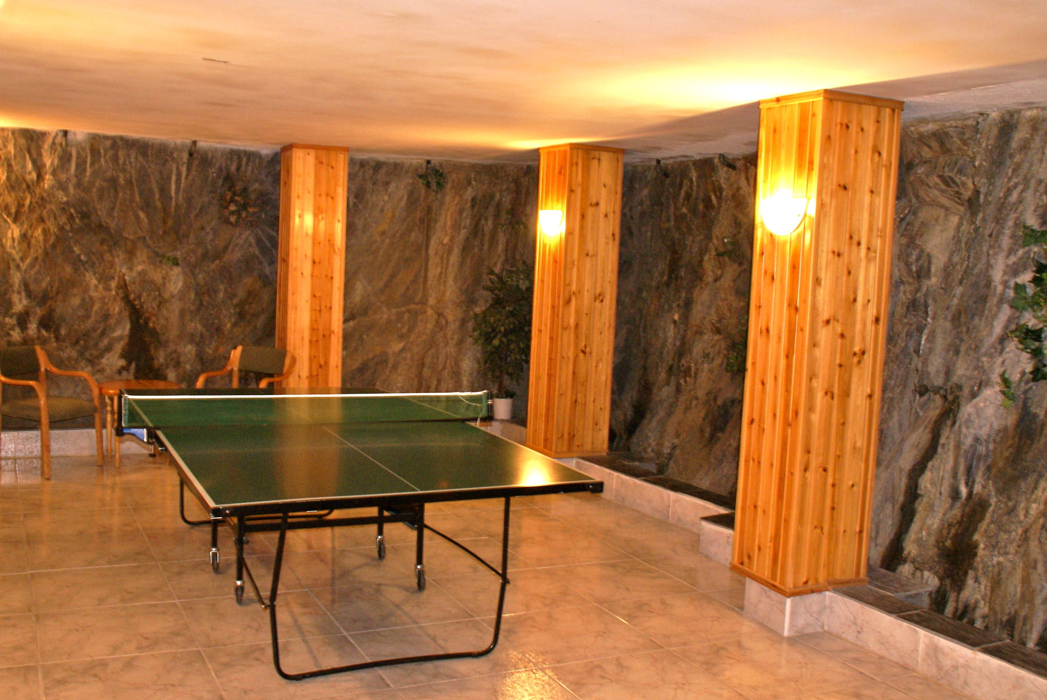 Une table de ping-pong dans une pièce aux murs de pierre et aux piliers en bois.