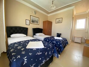 Een hotelkamer met twee bedden, een kledingkast, een klein bureau en een raam.