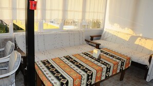 A sunlit room with a patterned sofa, a small table, and a chair. - Beyaz Kale (Denizli)
