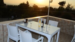 An outdoor patio with a glass table set for two, surrounded by white wicker chairs. - Beyaz Kale (Denizli)