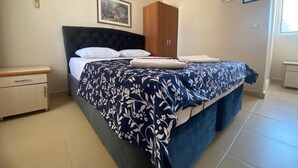 A bedroom with a bed, a nightstand, a wardrobe, and a framed picture on the wall. - Beyaz Kale (Denizli)