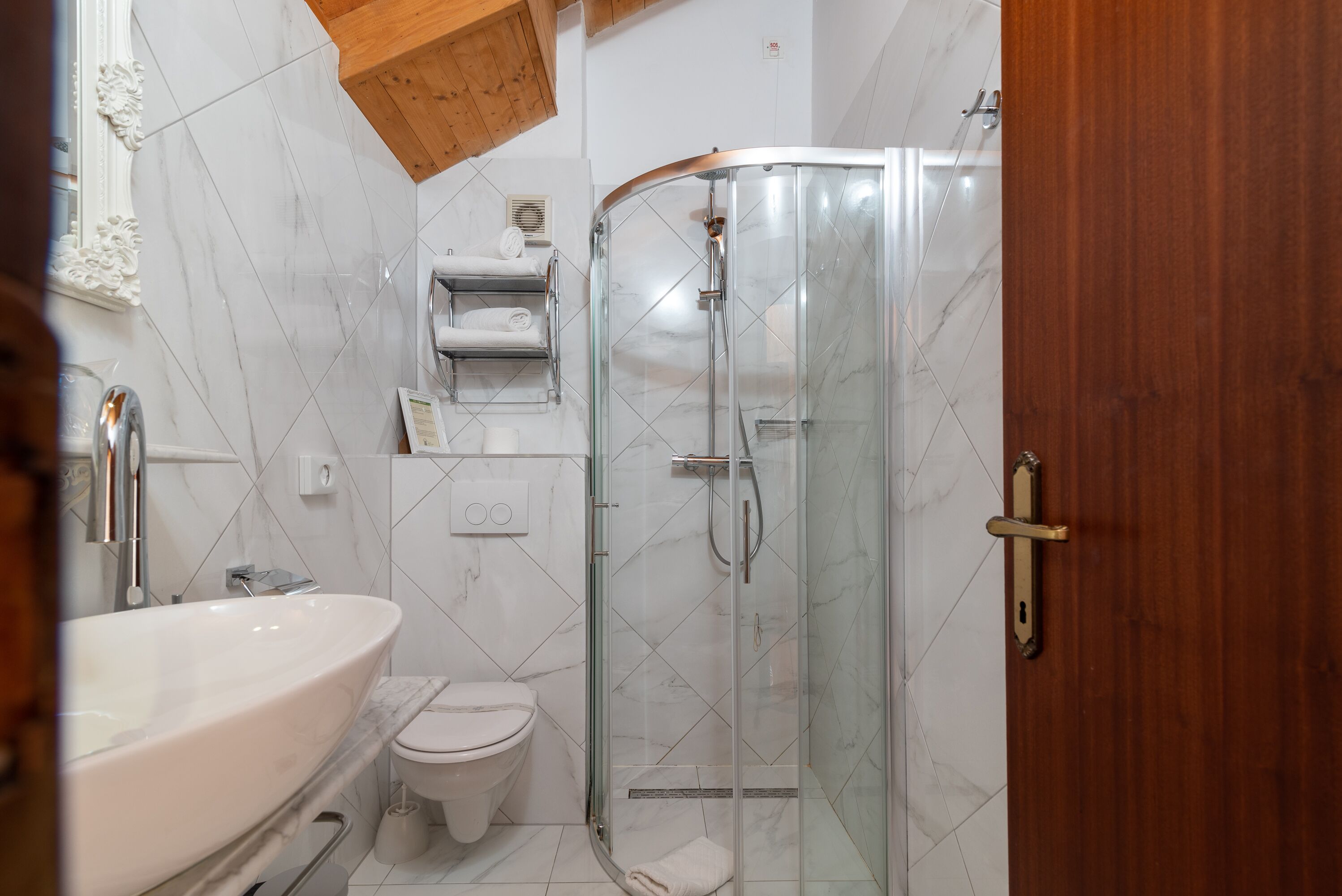 Een moderne badkamer met een douchecabine van glas, een witte wastafel en een toilet.