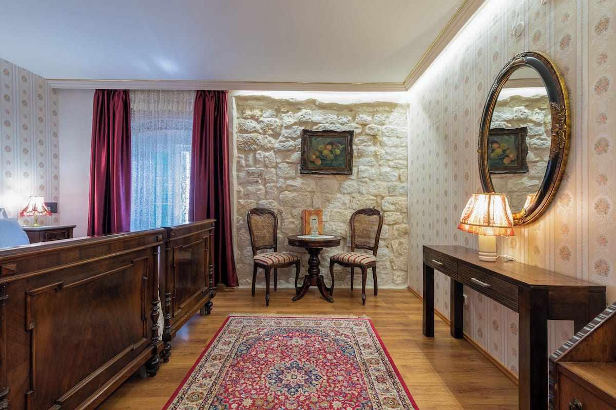 A room with a wooden bed, a small round table with chairs, a lamp, and a mirror on a dresser.