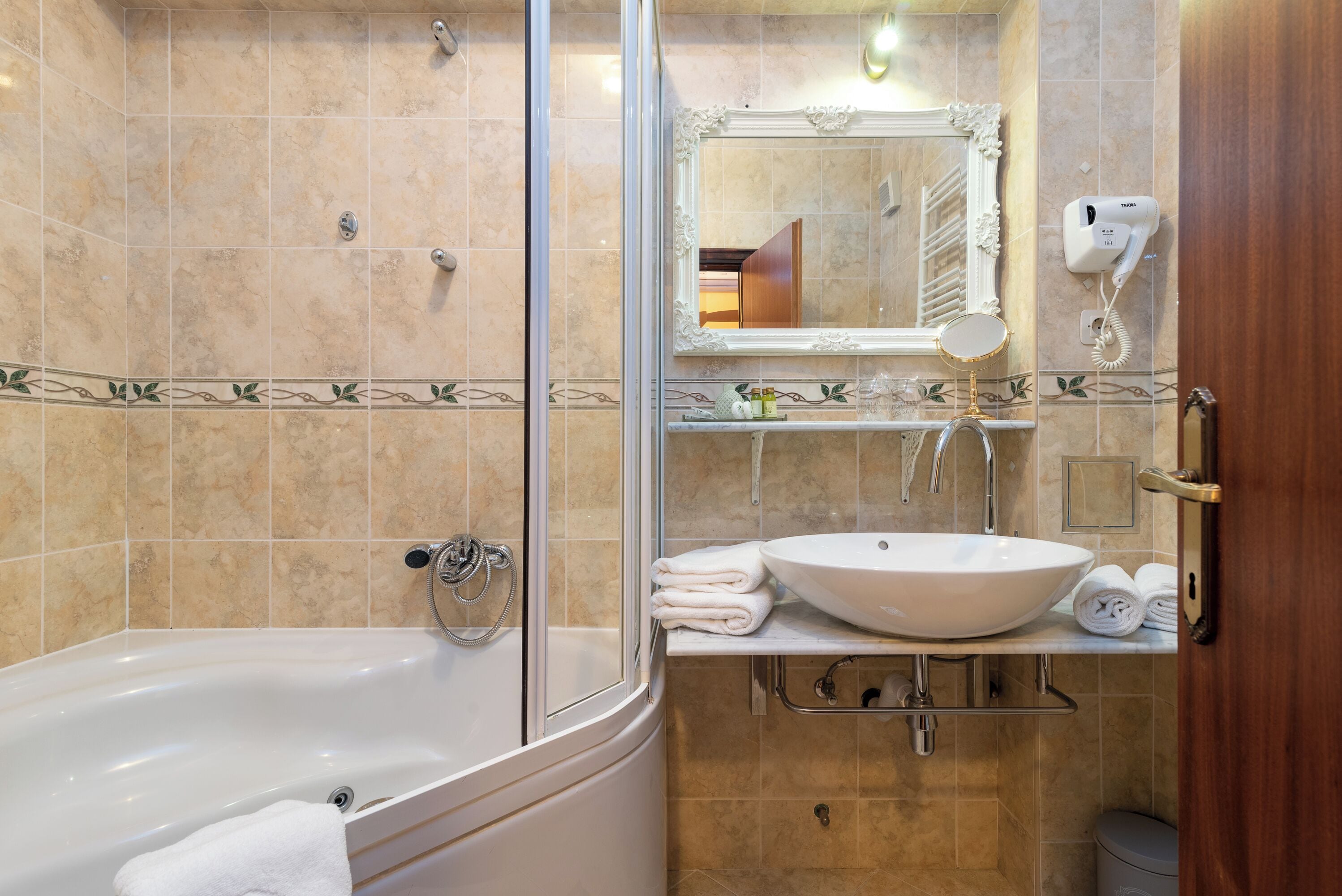 A bathroom with a bathtub, a sink, a mirror, and a hairdryer on the wall.