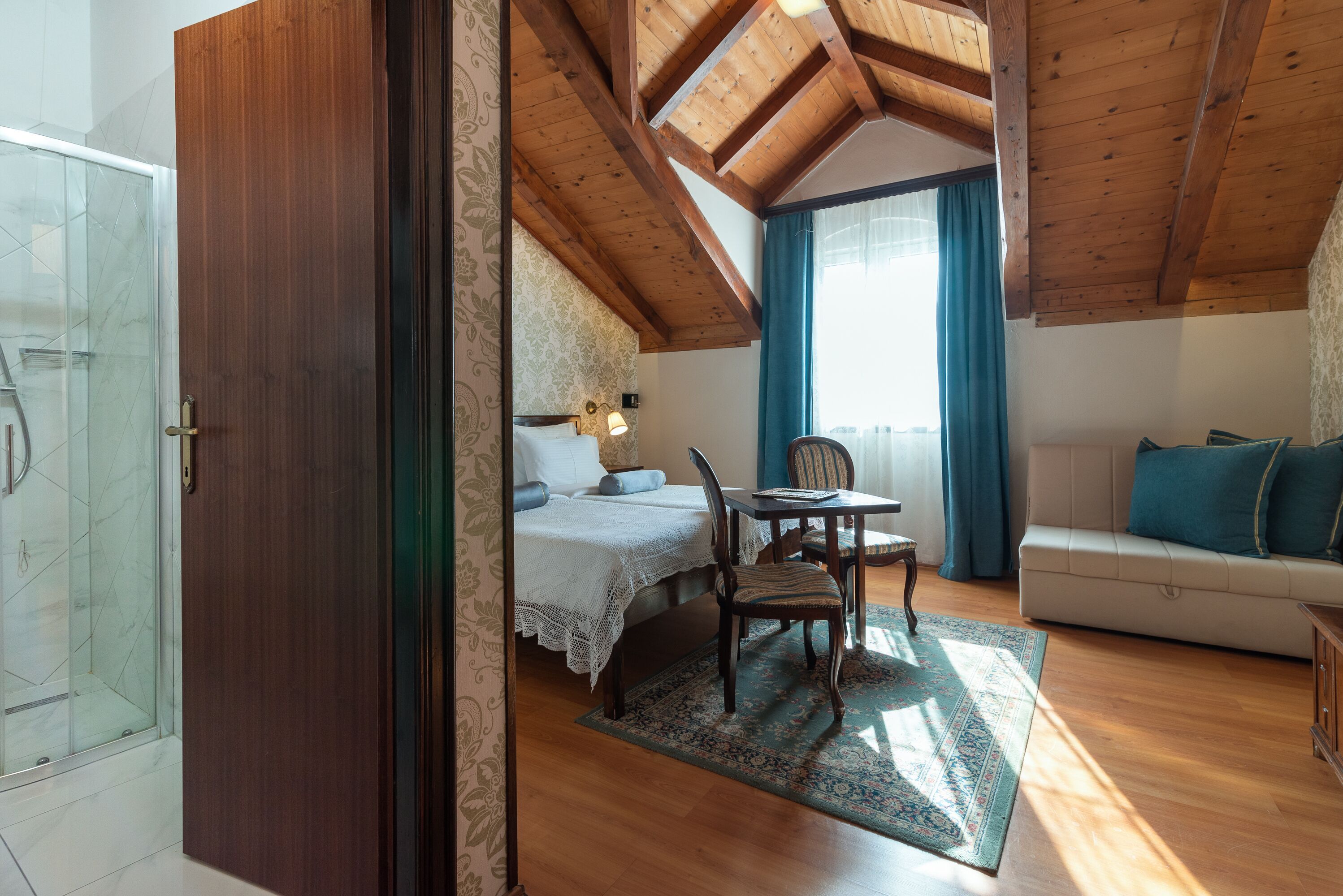 A bedroom with a wooden ceiling, a bed, a desk, and a sofa.