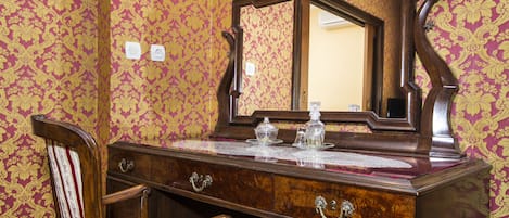 A wooden dresser with a mirror, drawers, and a chair.