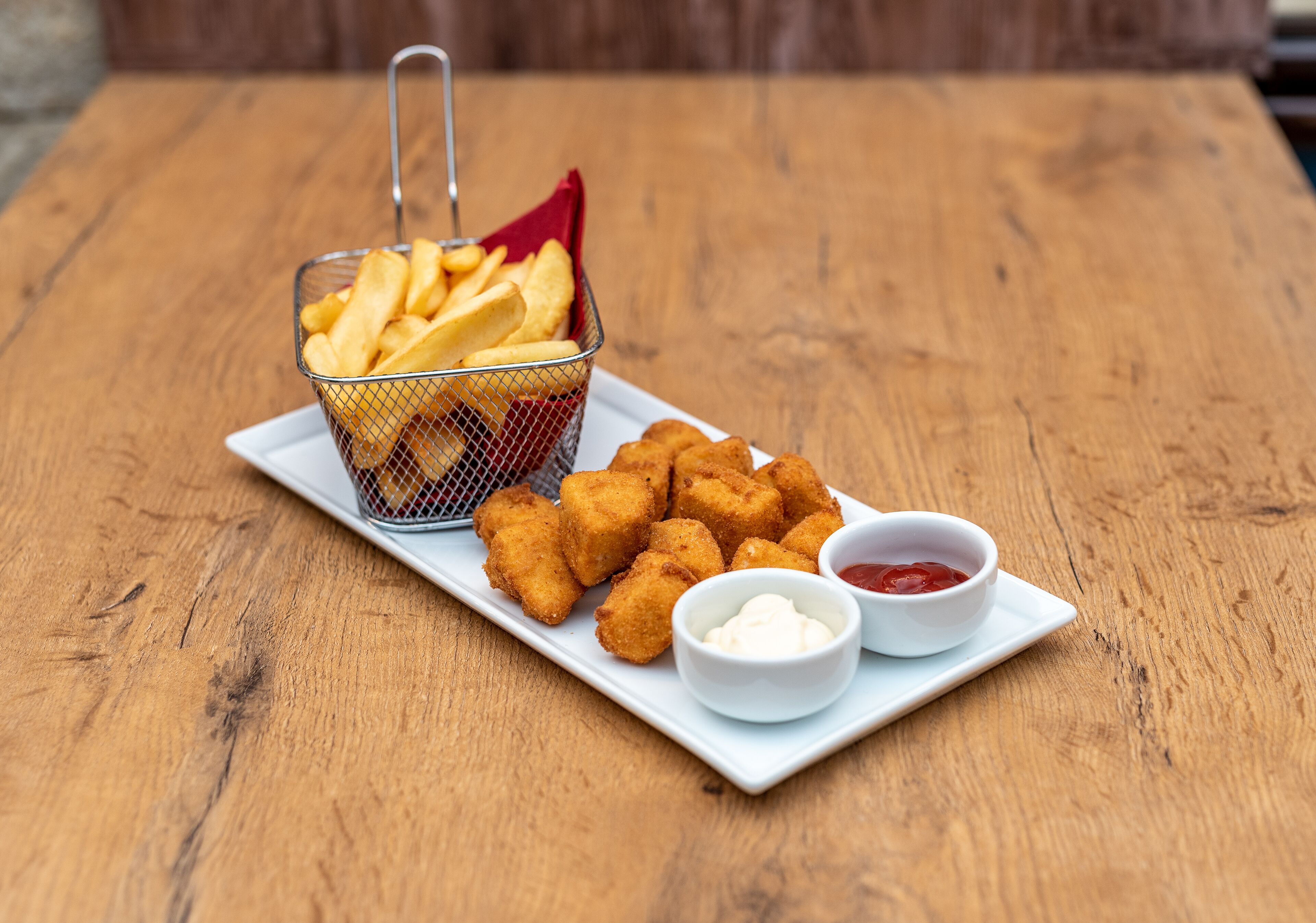 Eine Platte mit frittierten Speisen, darunter Tater Tots und Pommes Frites, serviert mit zwei Dipsaucen.
