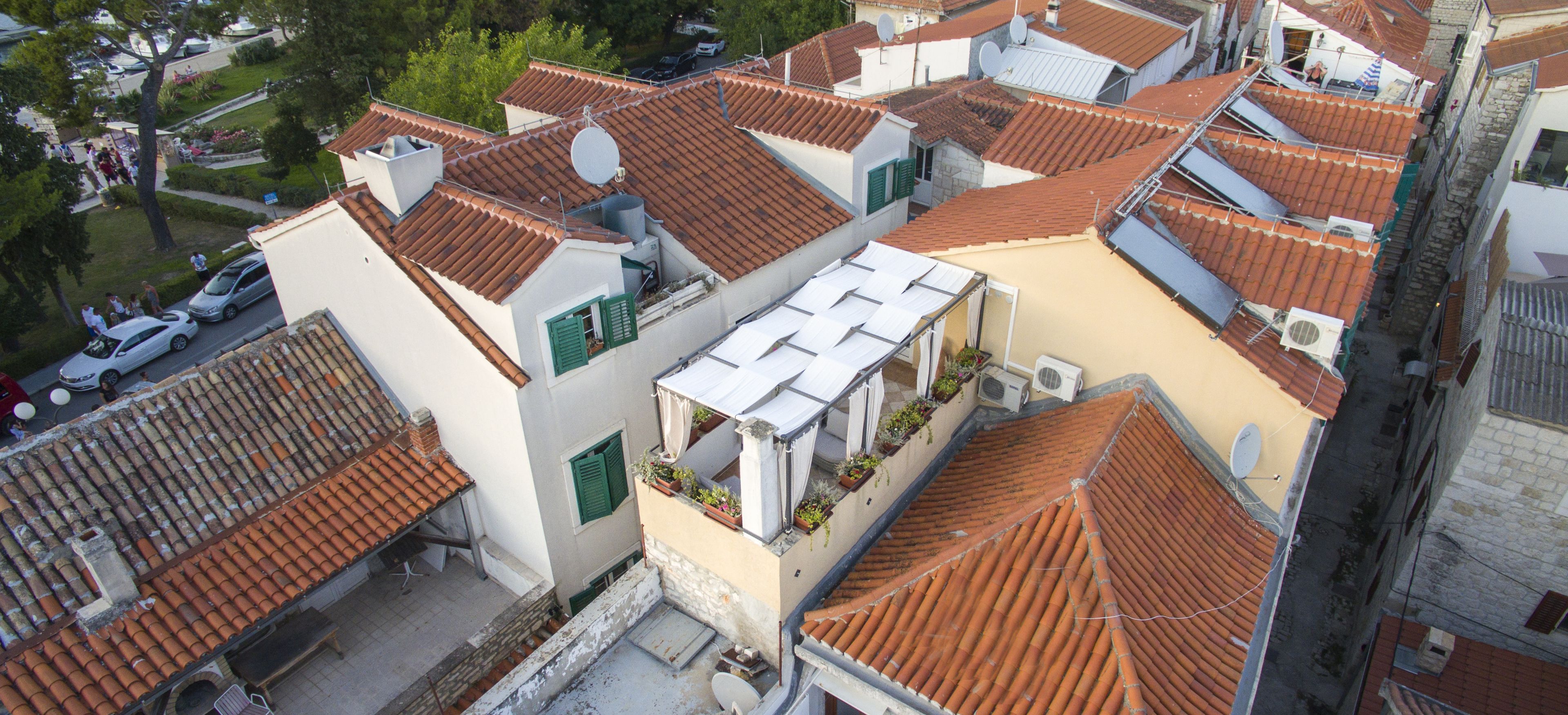 A residential area with terracotta-tiled roofs, satellite dishes, and satellite TV antennas.