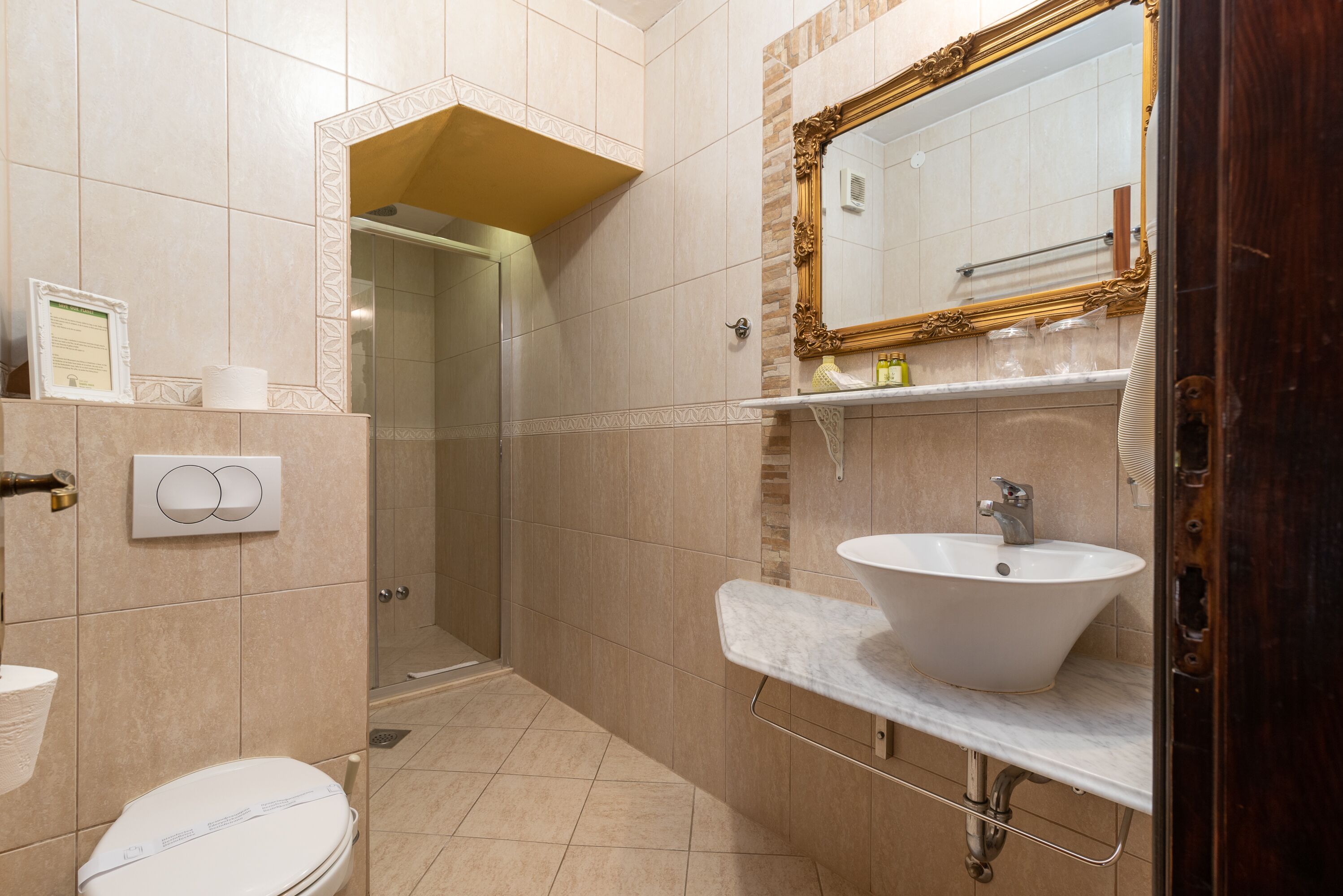 Baño con inodoro, lavabo, espejo y ducha.