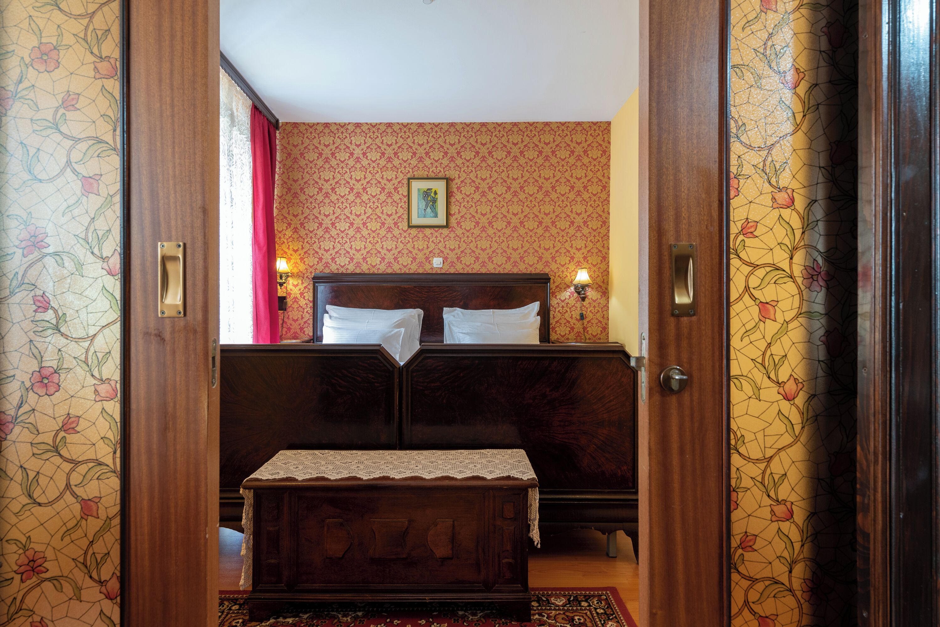 A room with a bed, a bedside table, and a small bench.