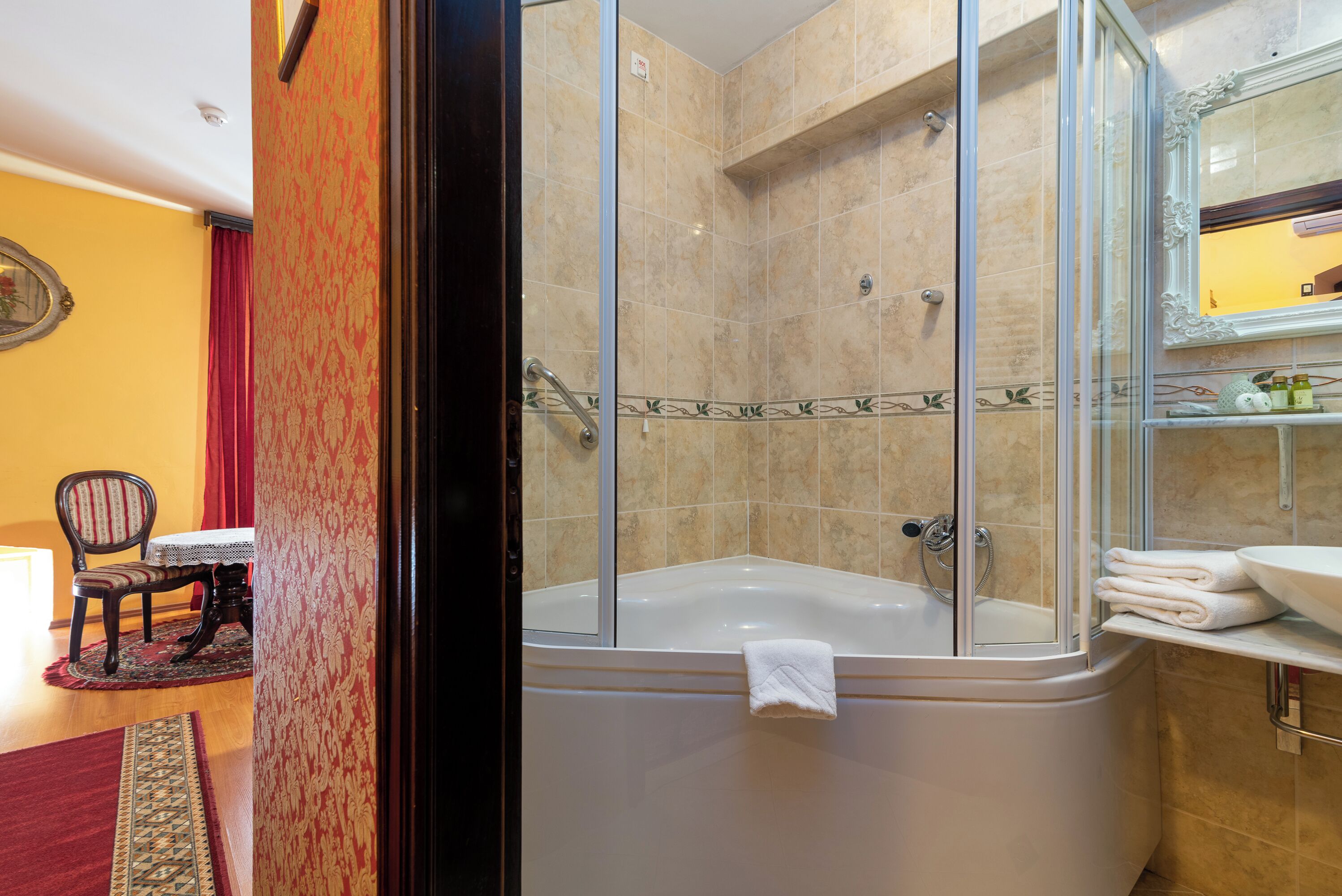 Een badkamer met een glazen douchecabine, een wit bad en een wastafel met spiegel.