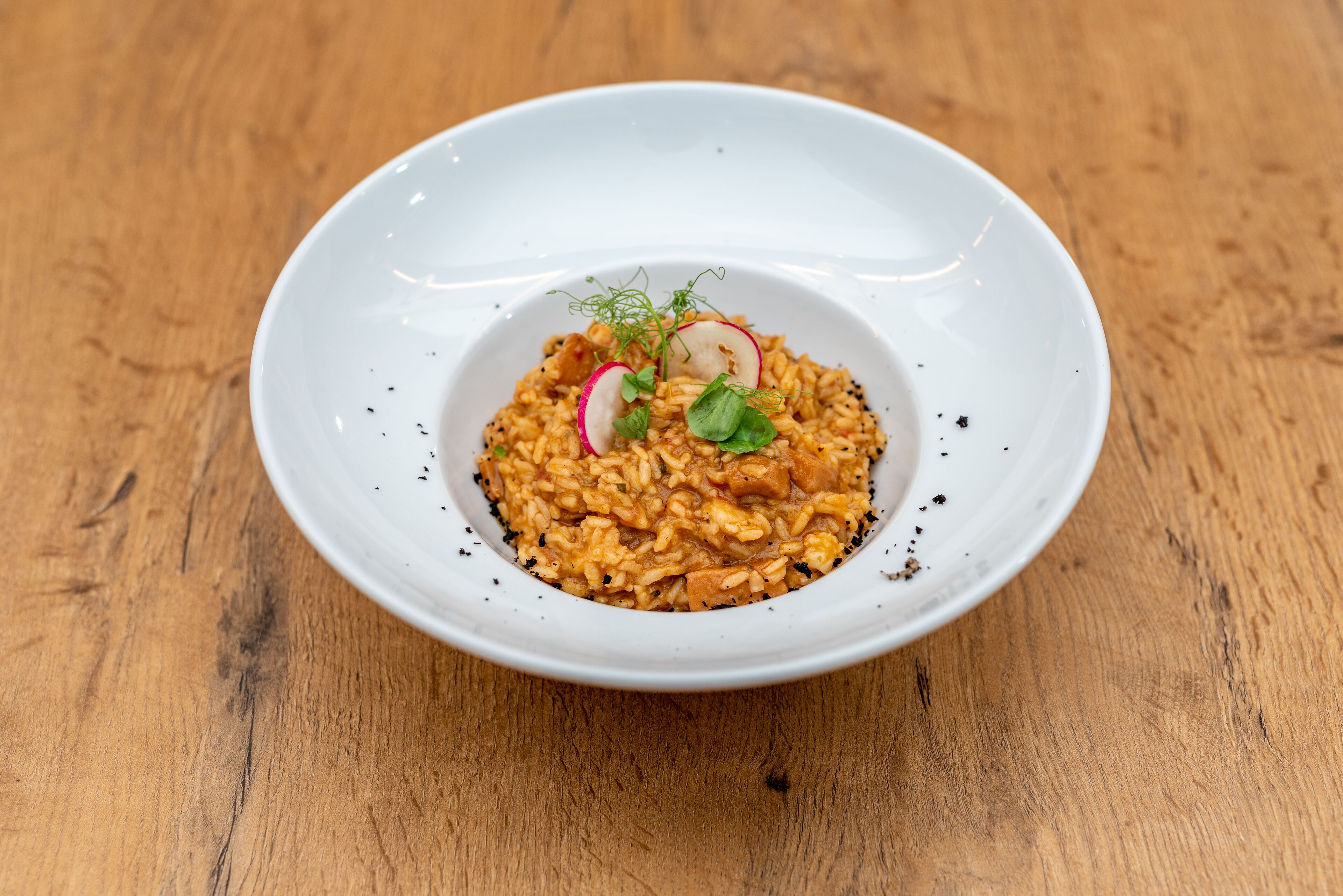 Un plato blanco con una porción de arroz y verduras sobre una mesa de madera.