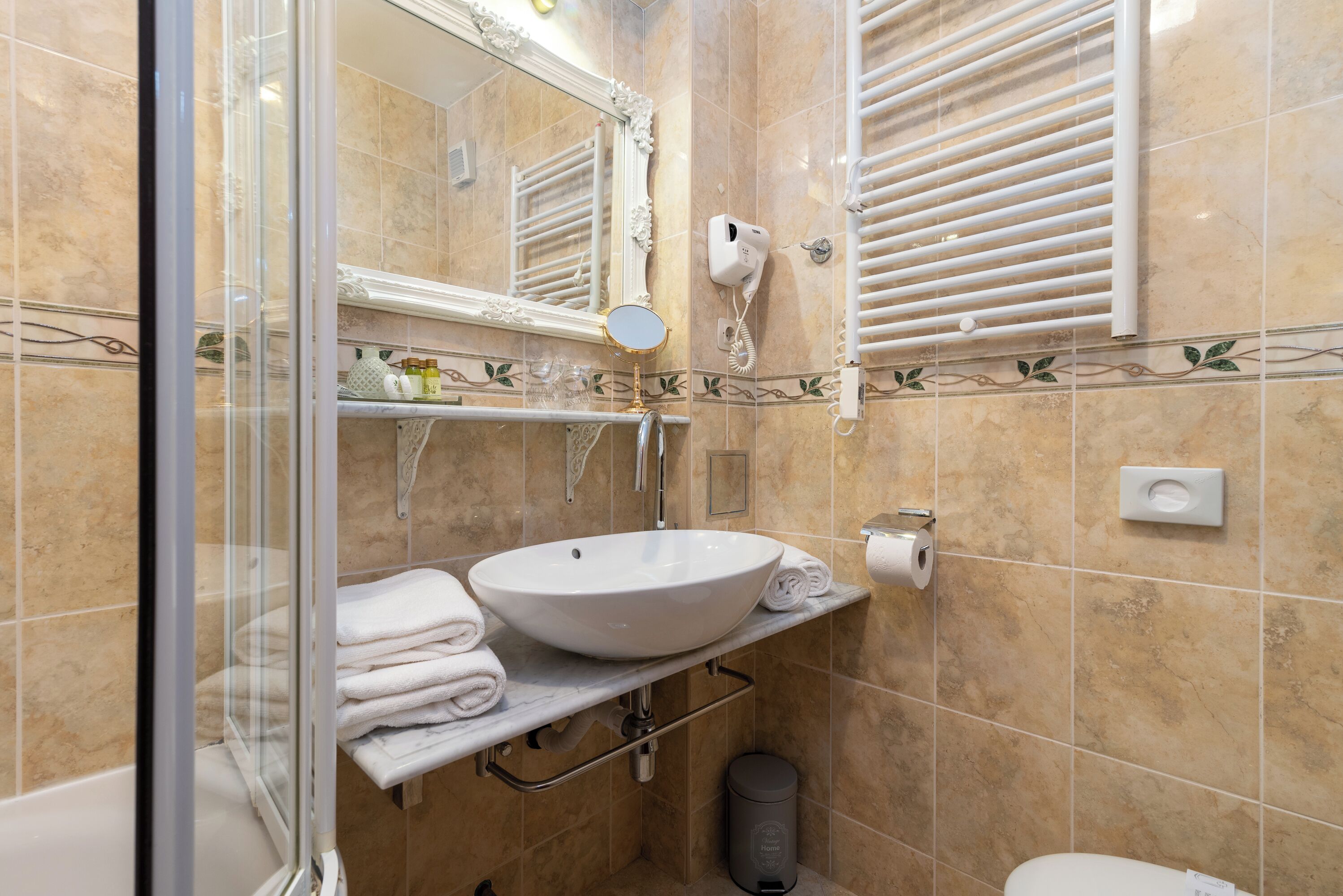 A bathroom with a white sink, a mirror, a towel rack, a hairdryer, and a toilet.