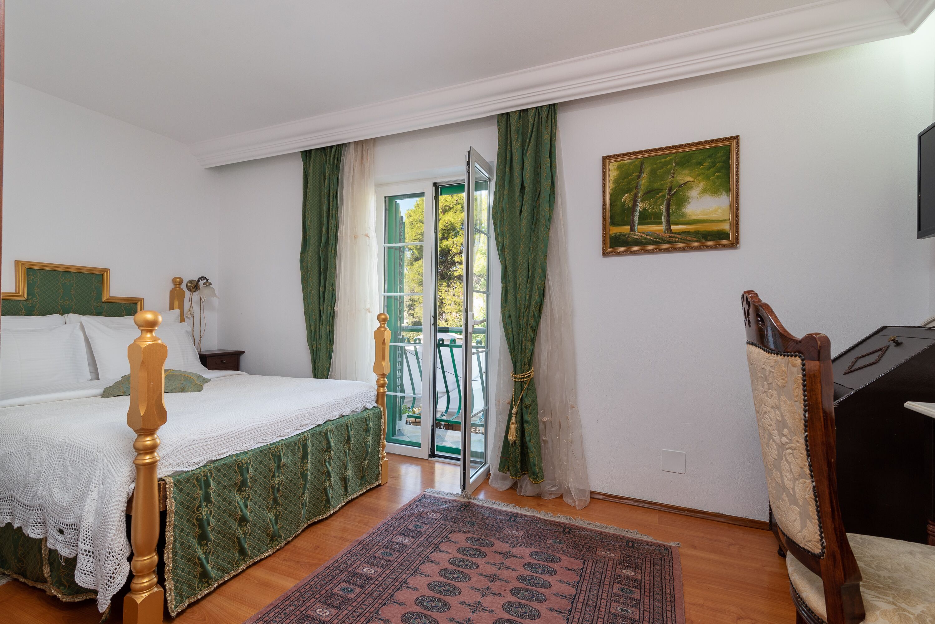 A bedroom with a bed, a chair, a painting, and a view through a door.