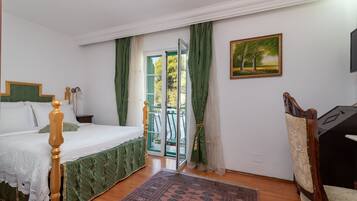 A bedroom with a bed, a chair, a painting, and a view through a door.