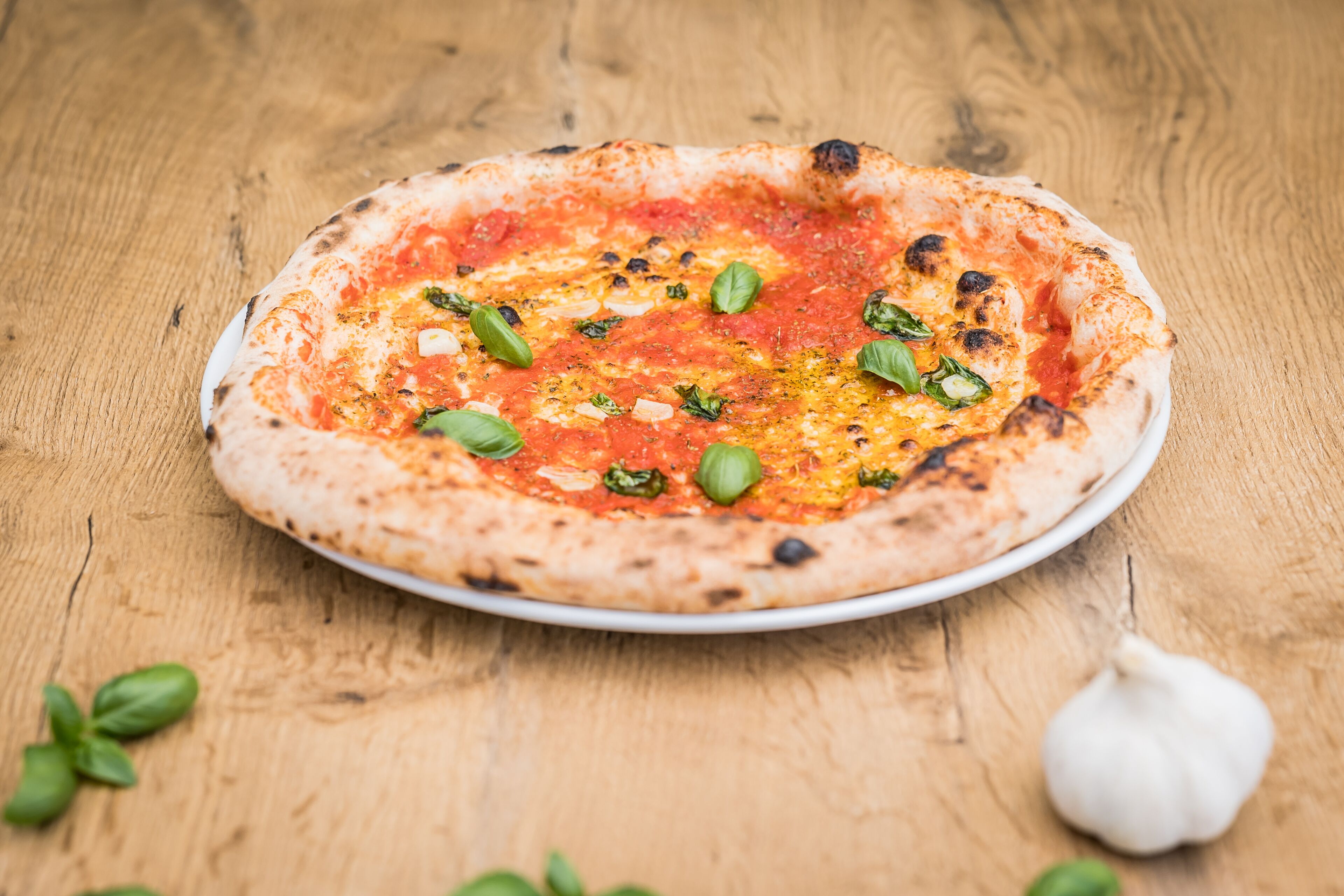 A pizza on a white plate with a wooden table background.