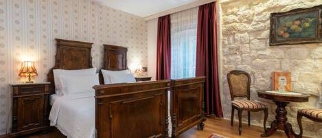 Un dormitorio tradicional con una cama con dosel de madera, una mesita de noche con lámpara, una silla y una pequeña mesa.