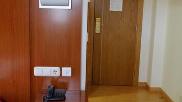 A wooden door with a mailbox, a phone, and a wall socket.
