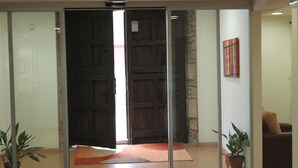 A reception area with a wooden door, a stone wall, and a colorful artwork on the wall. - Agorreta (Galar)