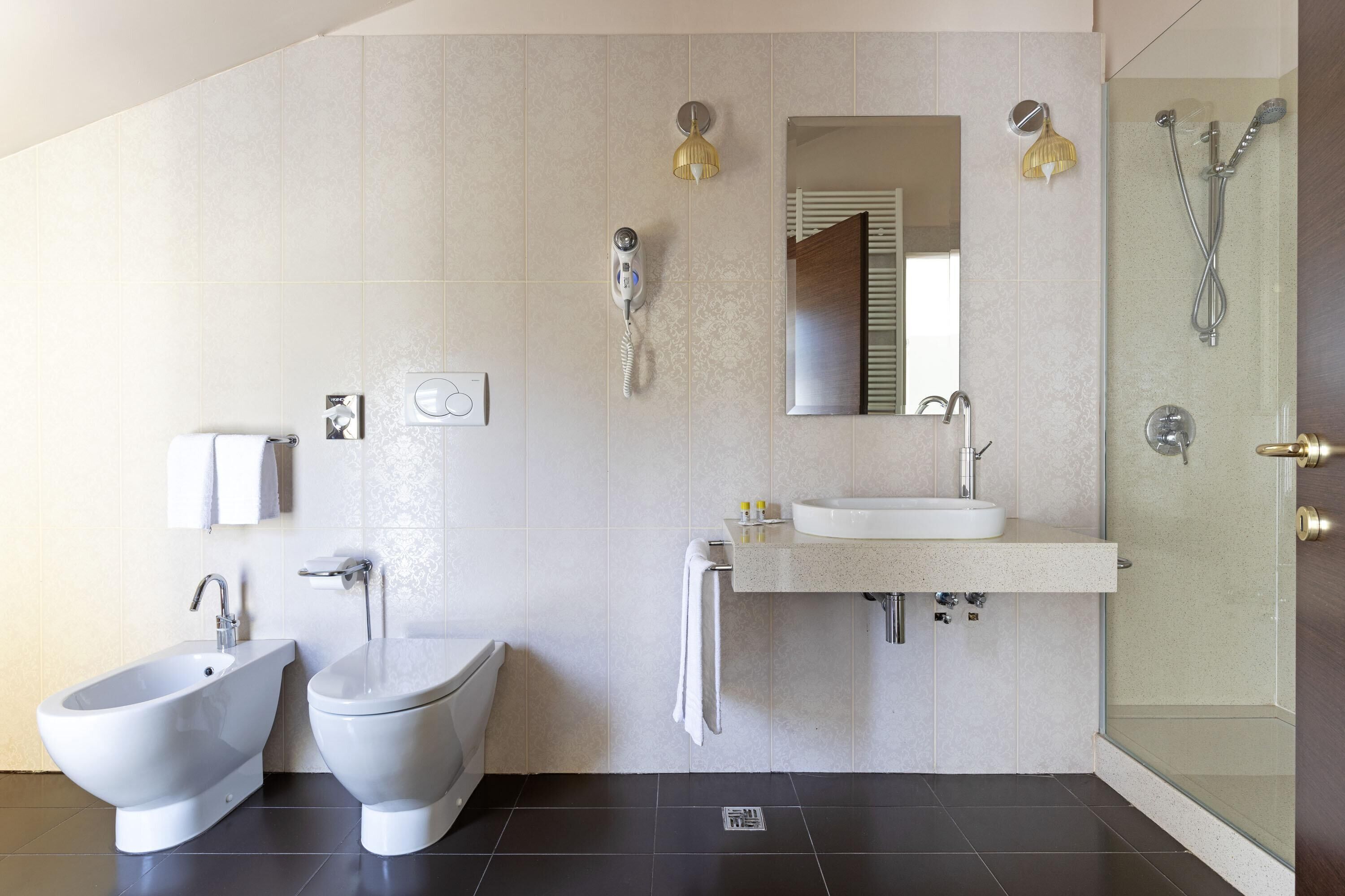 Un baño moderno con bidé, inodoro, lavabo y ducha con mampara de vidrio.