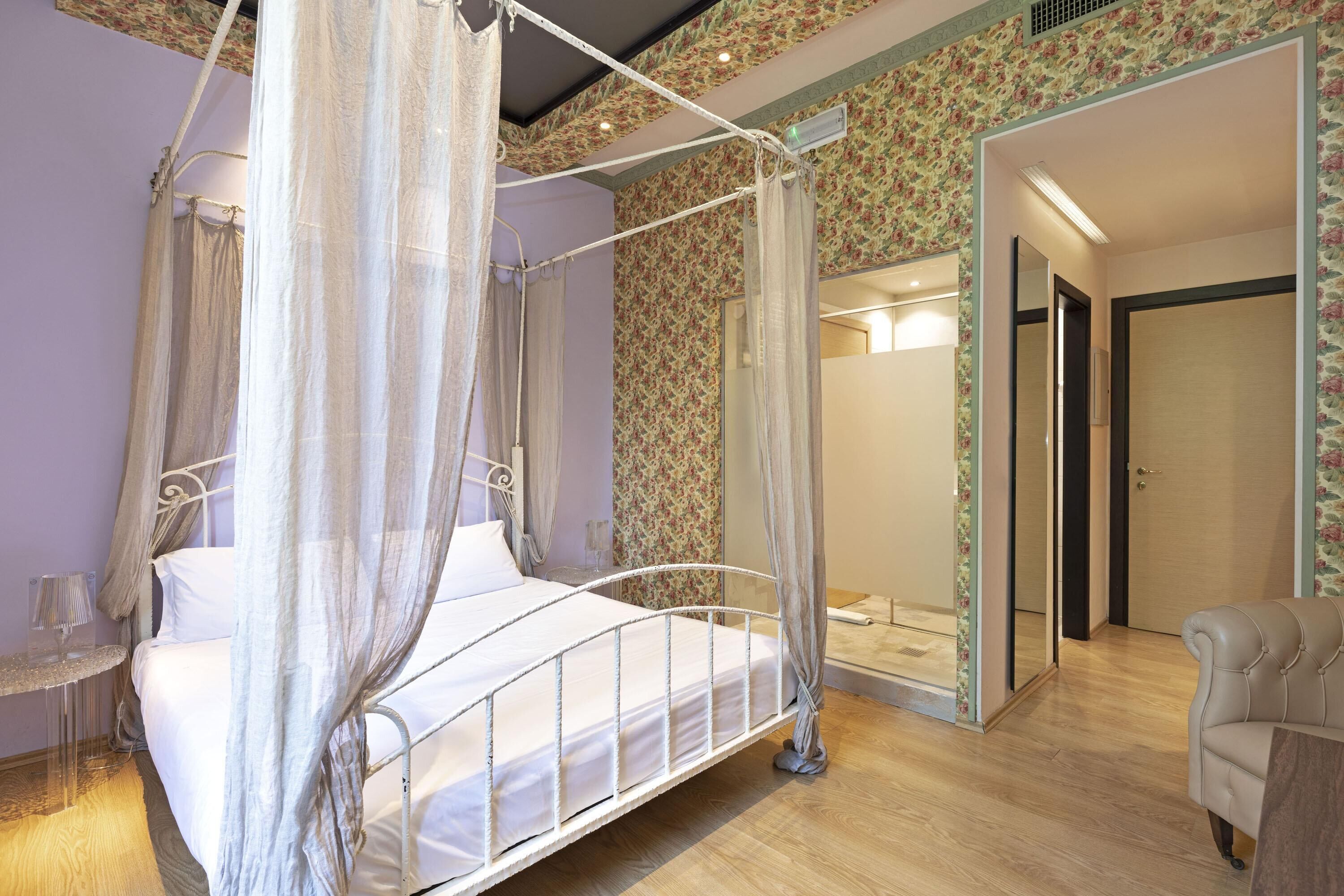A four-poster bed with a canopy, a bedside table, and a mirror.