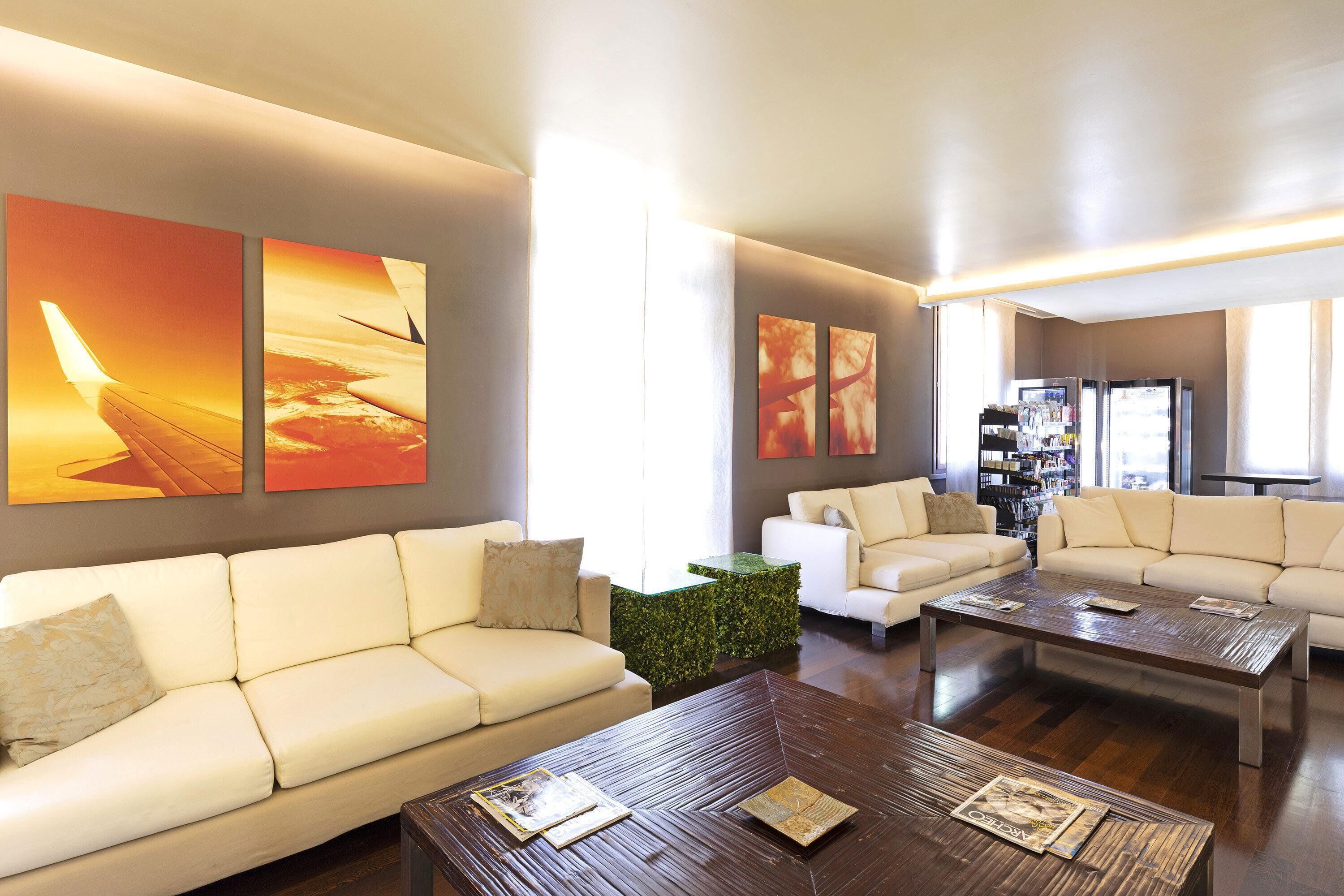 A modern living room with two white sofas, a wooden coffee table, and abstract wall art.