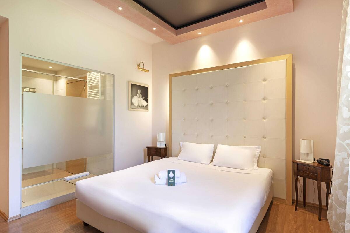 A hotel room with a large bed, a wardrobe, a bedside table, and a nightstand.