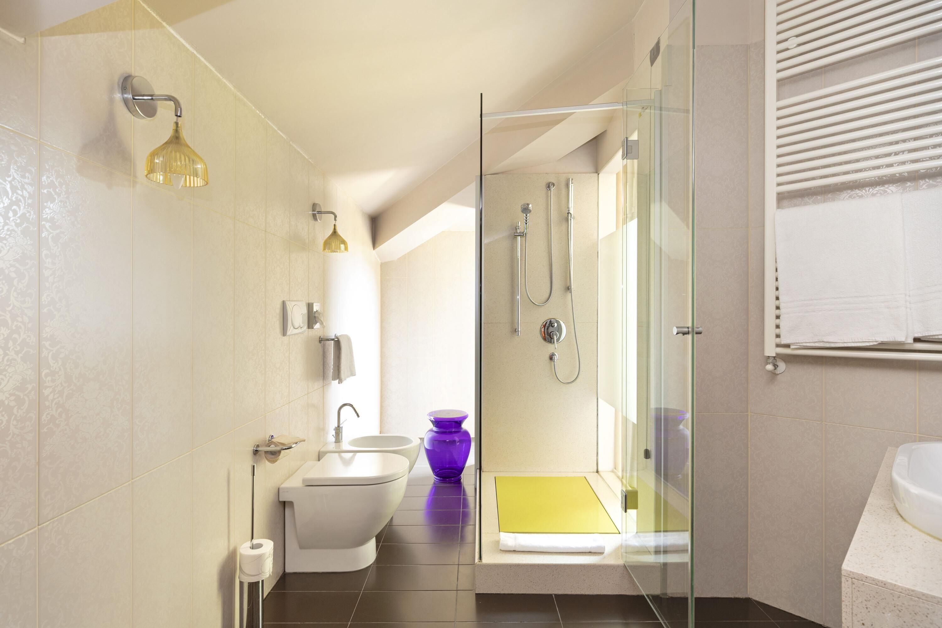 Une salle de bain moderne avec une douche à parois de verre, un lavabo blanc et une baignoire jaune.