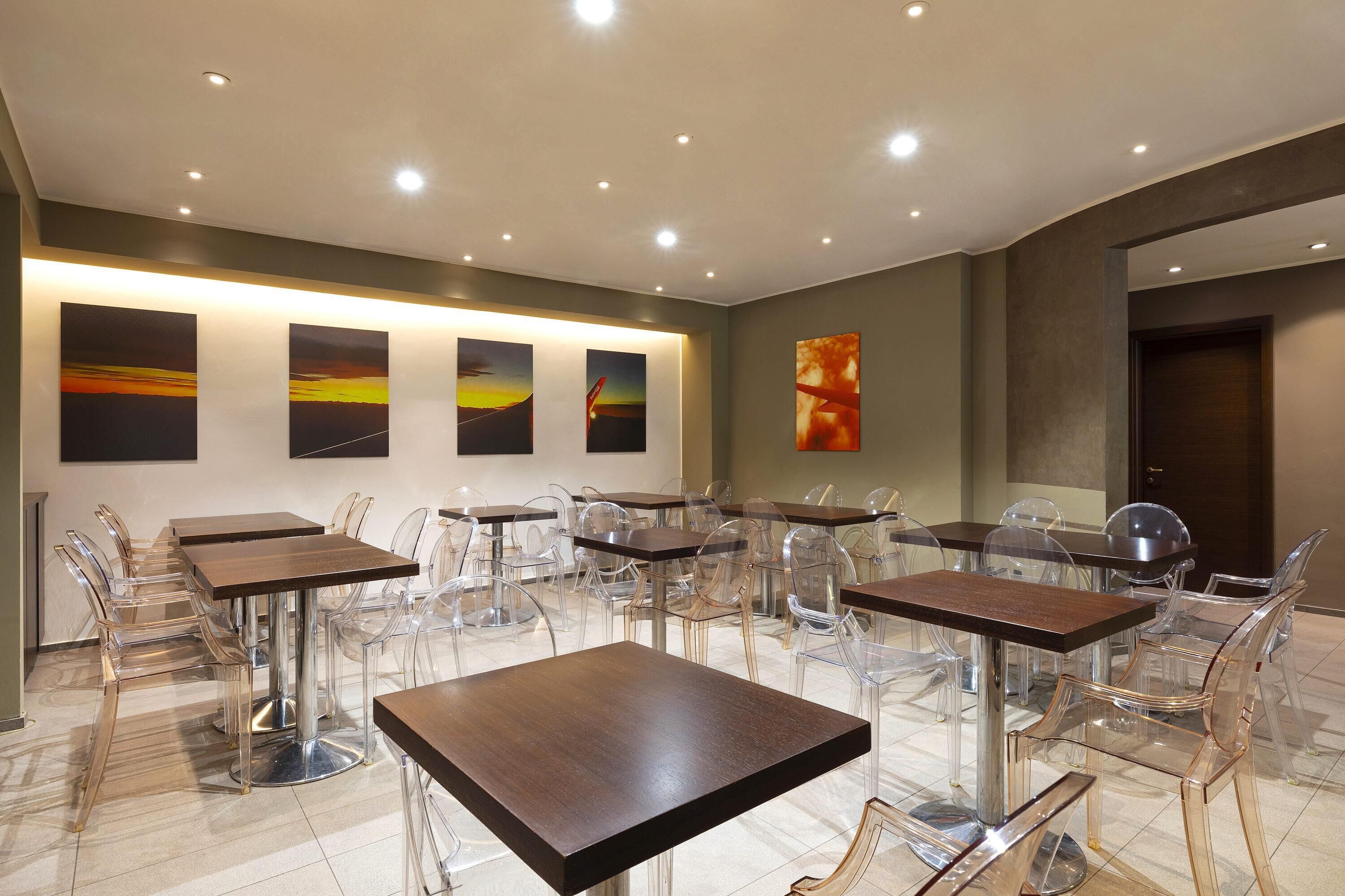 A modern dining area with multiple tables and chairs, featuring clear glass chairs and wooden tables.