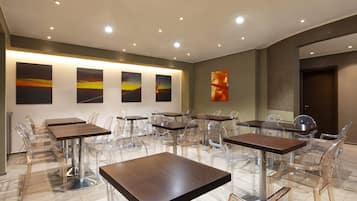 A modern dining area with multiple tables and chairs, featuring clear glass chairs and wooden tables.
