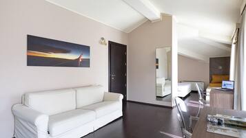 Un salon moderne avec un canapé en cuir blanc, une table à manger avec des chaises, un tableau accroché au mur et une porte donnant sur une autre pièce.