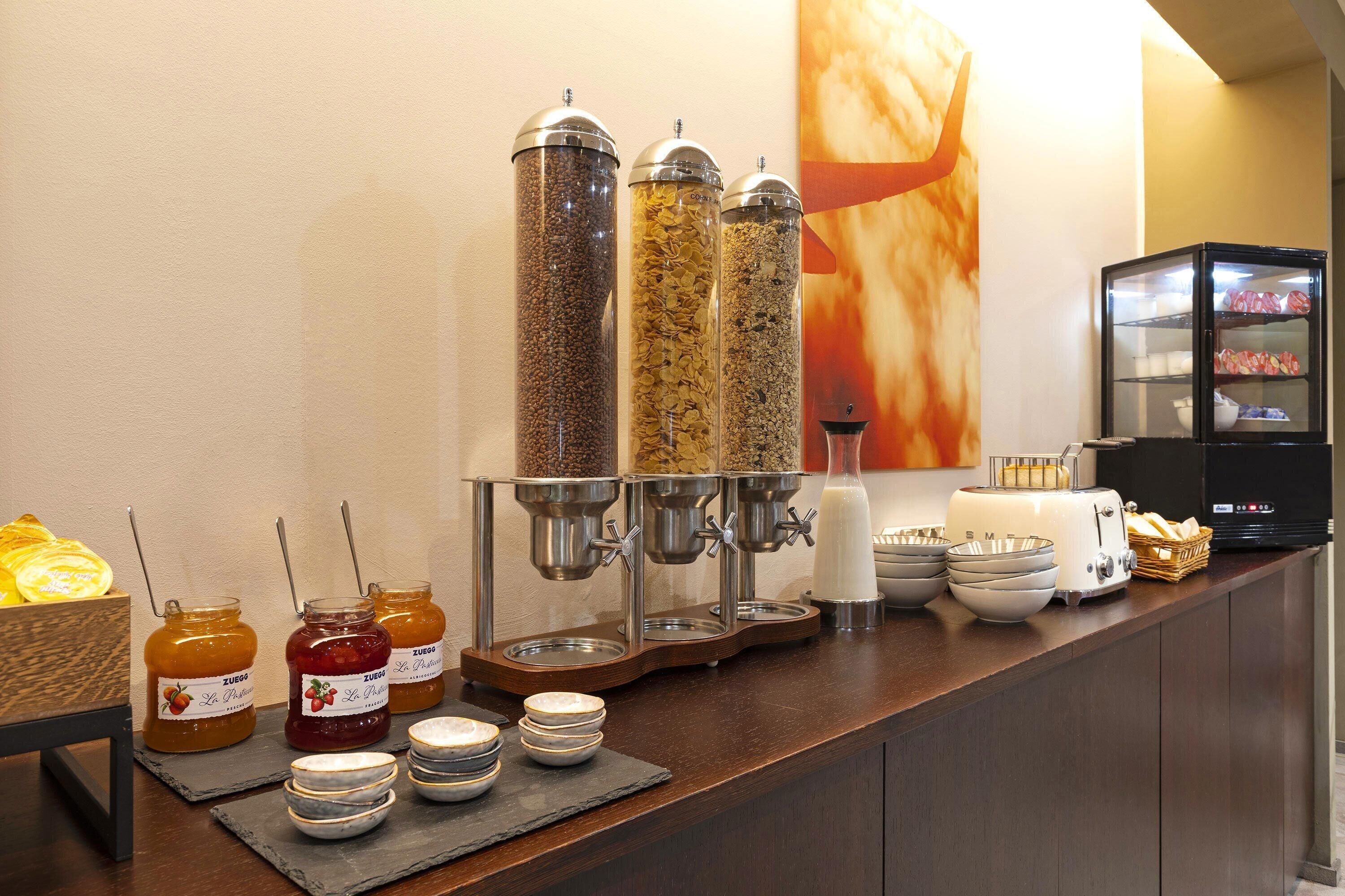 Een ontbijtbuffet met potten jam, een koffieapparaat en een broodrooster.