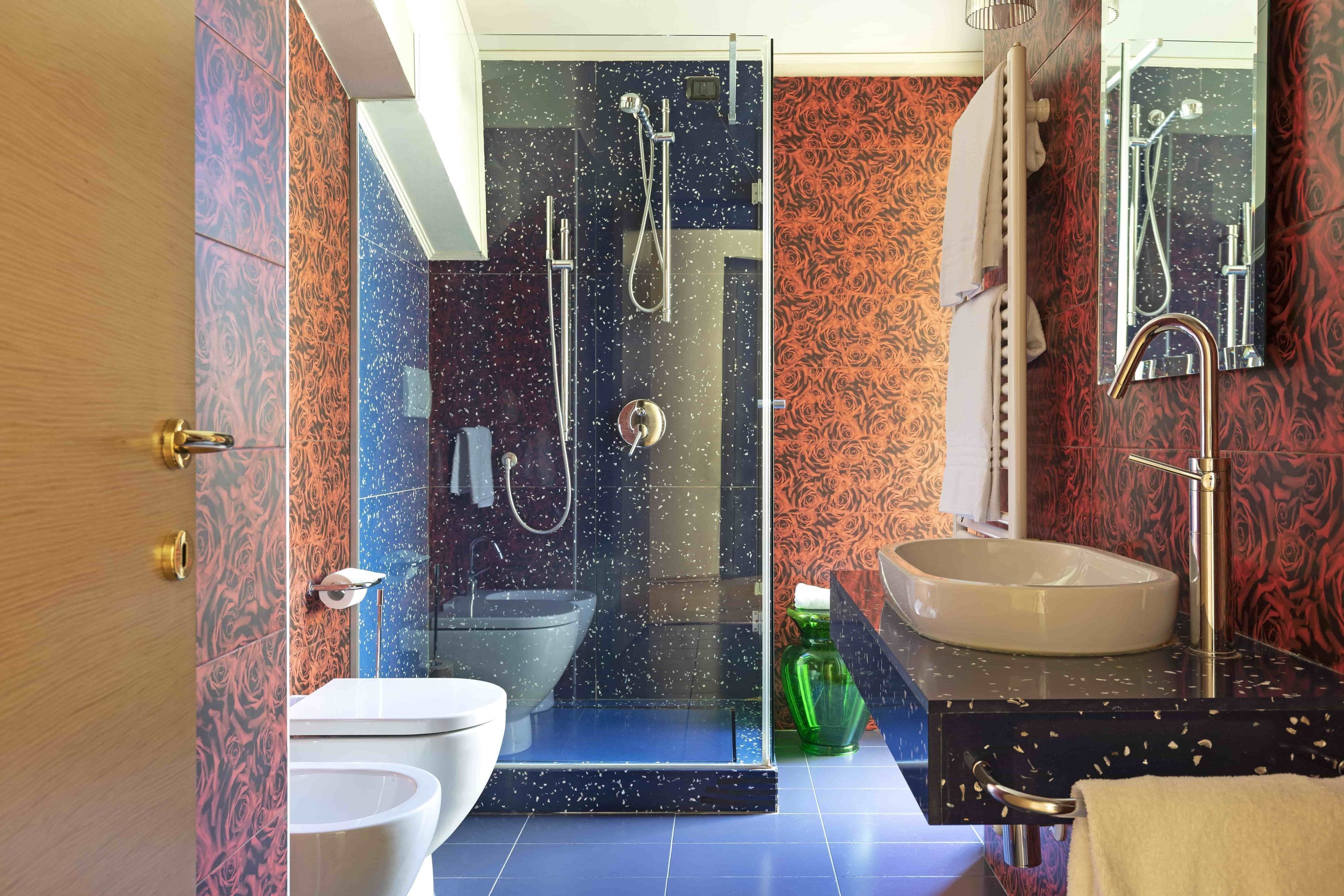 Un baño moderno con ducha envuelta en vidrio, inodoro blanco y un lavamanos grande con espejo.